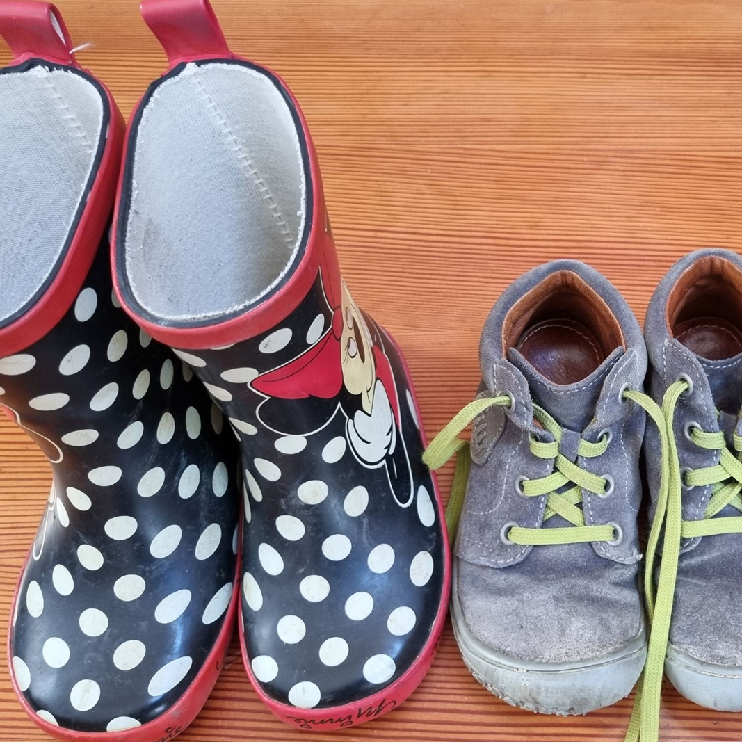 Blaue Gummistiefel mit weißen Punkten und graue schmutzige Kinderhalbschuhe